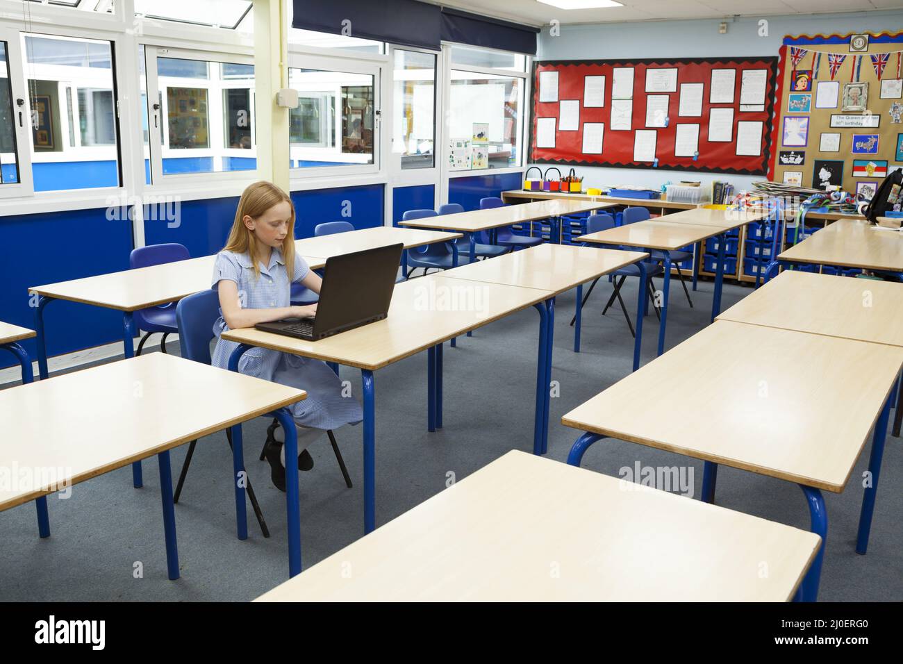 Scuola primaria ragazza caucasica usando un computer portatile in un aula vuota Foto Stock