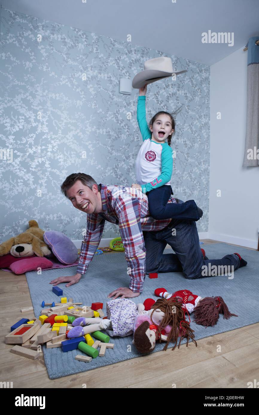 Pre-teen ragazza caucasica avente un piggyback ride da suo padre nella loro lounge Foto Stock