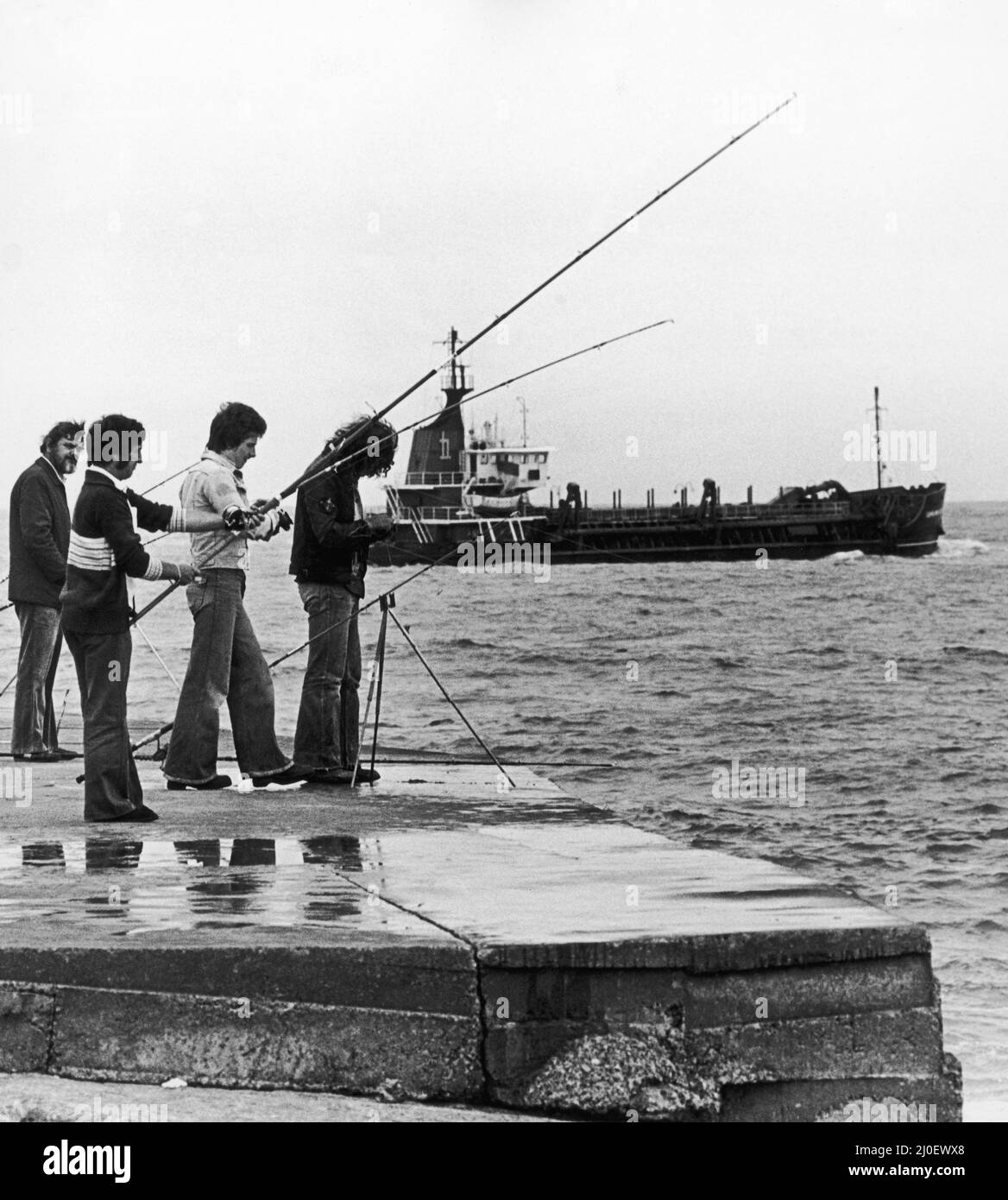 Questi quattro uomini hanno ovviamente caduto linea di gancio e sinker per il bug angling.Braving gli elementi che sperano di catturare merluzzo o sgombro fuori dalla Gare Sud. I pescatori sono ignari del Tee e Hartlepool Port Authority drager andare vicino. 4th settembre 1978 Foto Stock