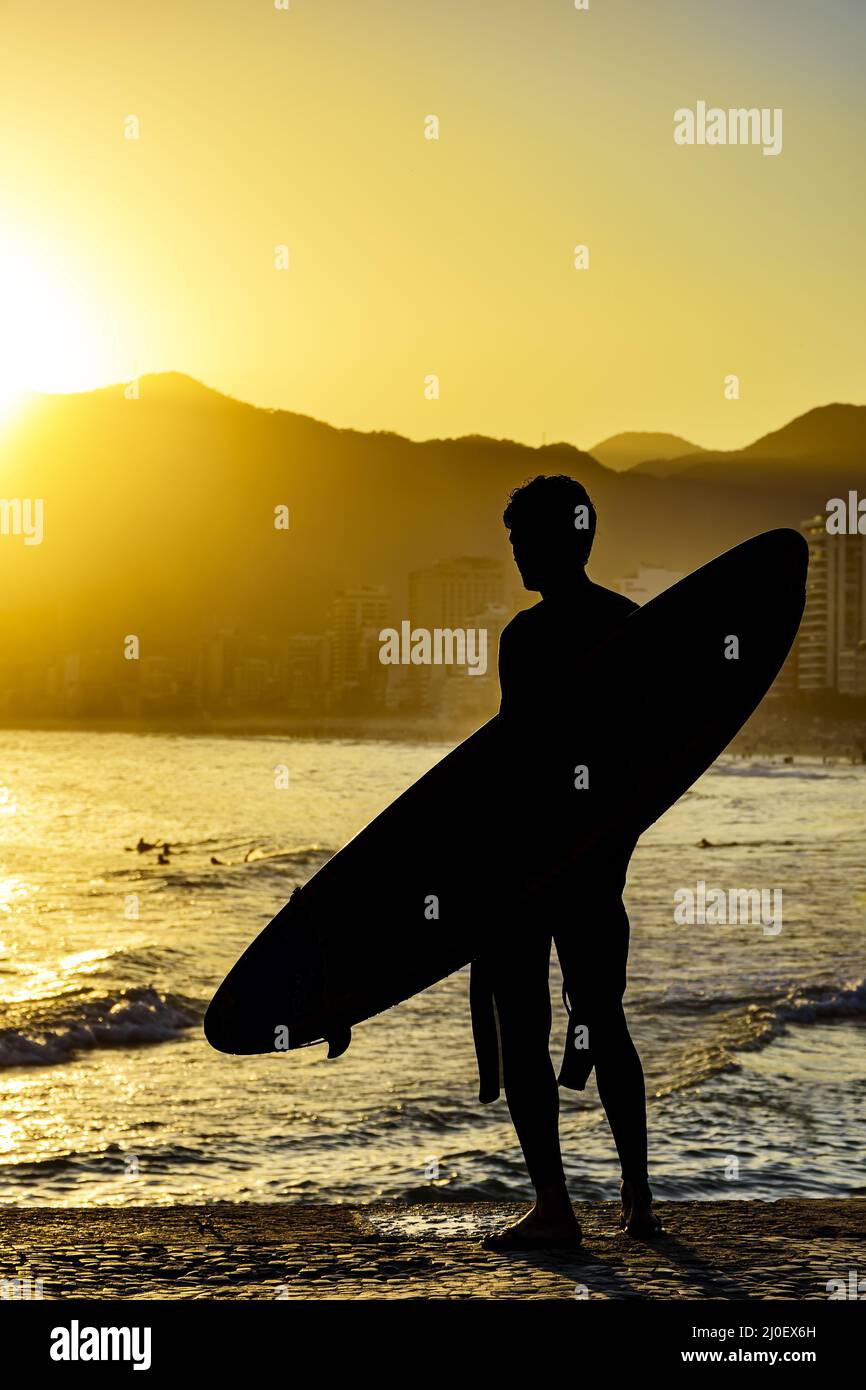 Silhouette surfista con la sua longboard che guarda la spiaggia di Iapnema Foto Stock Silhouette surfista con la sua longboard che guarda la spiaggia di Iapnema Foto Stock
