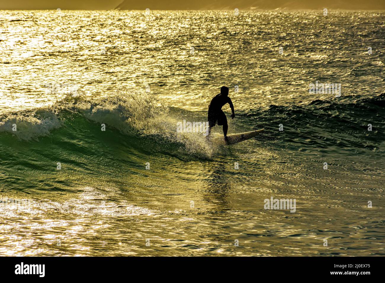 Surfista sulle onde della spiaggia di Ipanema al tramonto Foto Stock