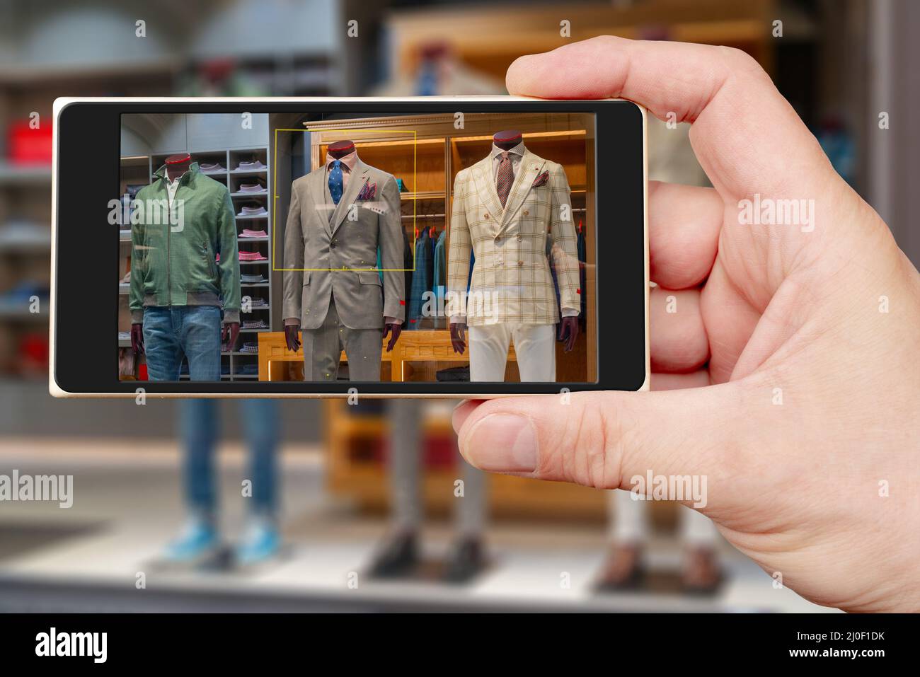 Manichino maschile sullo schermo dello smartphone. Vendita di abbigliamento uomo. Vetrina negozio di abbigliamento. Foto Stock