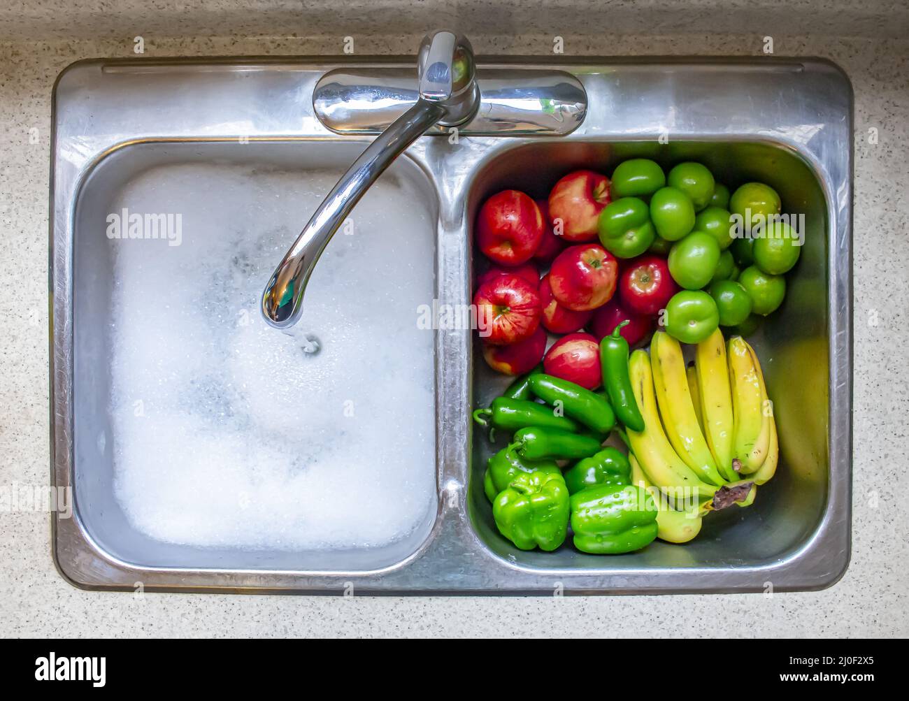 Lavare verdure e frutta su un canto con acqua corrente e sapone Foto Stock
