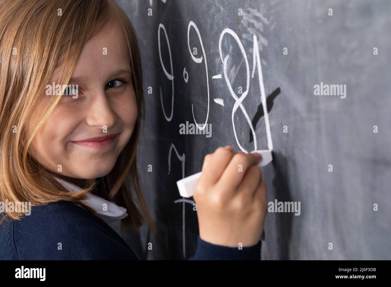 Lo studente risolve un problema di matematica in piedi alla lavagna nella sua classe. Foto Stock