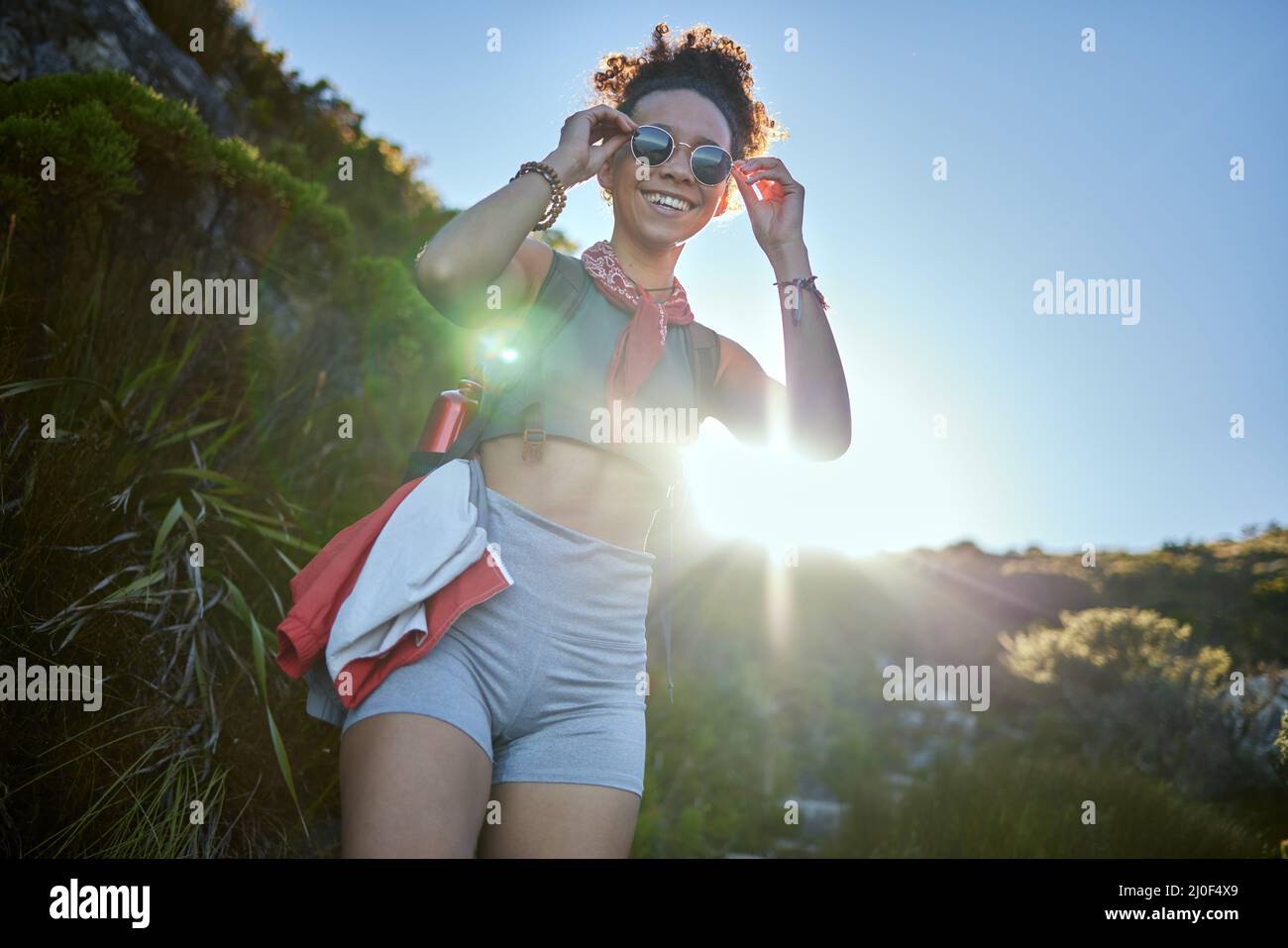 E 'folle raffreddamento qui. Scatto di una giovane donna che indossa i suoi occhiali da sole mentre fuori su un'escursione. Foto Stock
