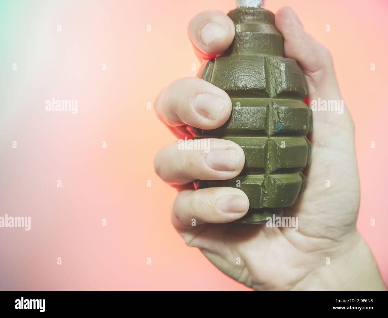 La mano tiene una vecchia granata sovietica su sfondo rosa. Foto di primo piano Foto Stock