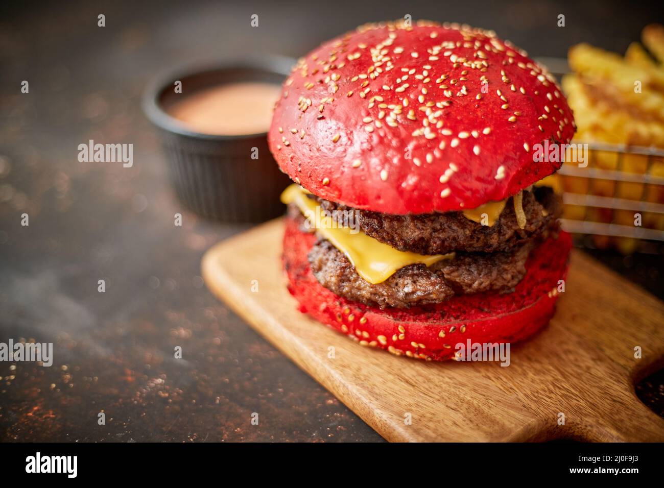 Hamburger fatto in casa di formaggio rosso di sesamo doppio bacon. Servita con patatine fritte su tavola di legno. Foto Stock