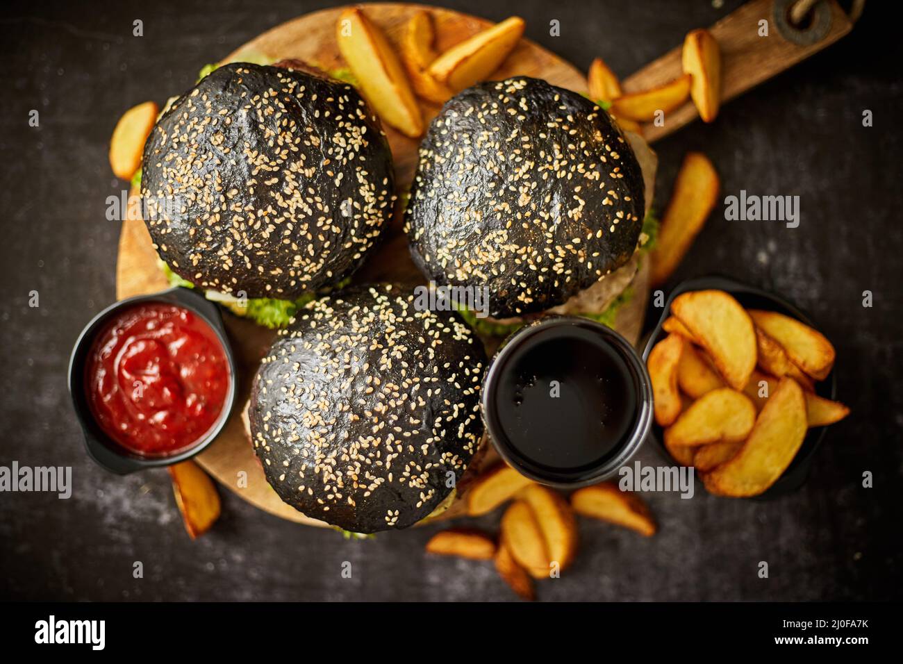 Hamburger neri e patatine fritte con salsa Foto Stock