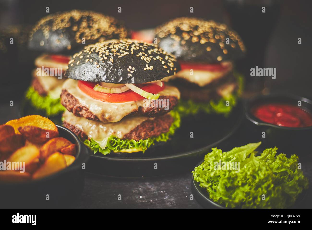 Appetitosi hamburger neri e patate fritte Foto Stock