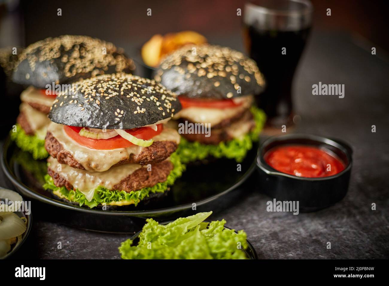 Appetitosi hamburger neri e patate fritte Foto Stock