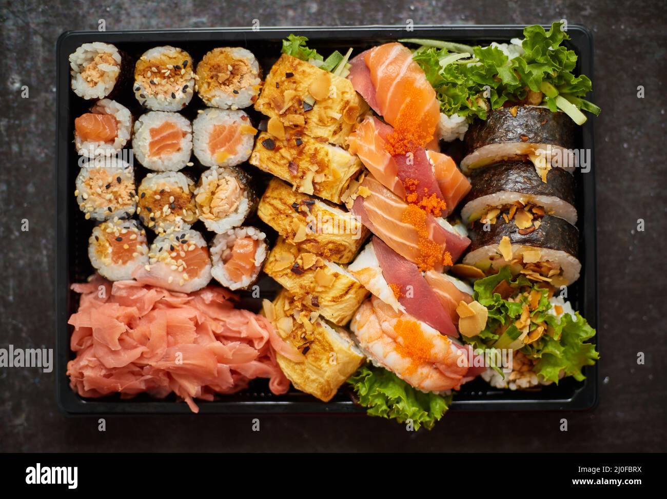 Primo piano di vari set di sushi in scatola di consegna in plastica nera. Vista dall'alto Foto Stock