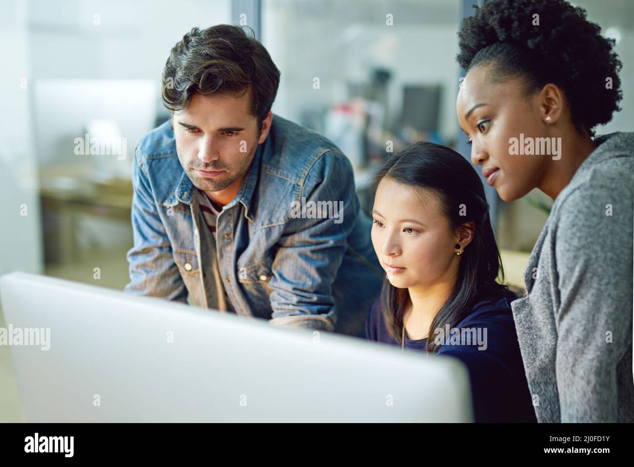 Tre società. Girato di un gruppo di uomini d'affari creativi riuniti intorno a un computer in ufficio. Foto Stock