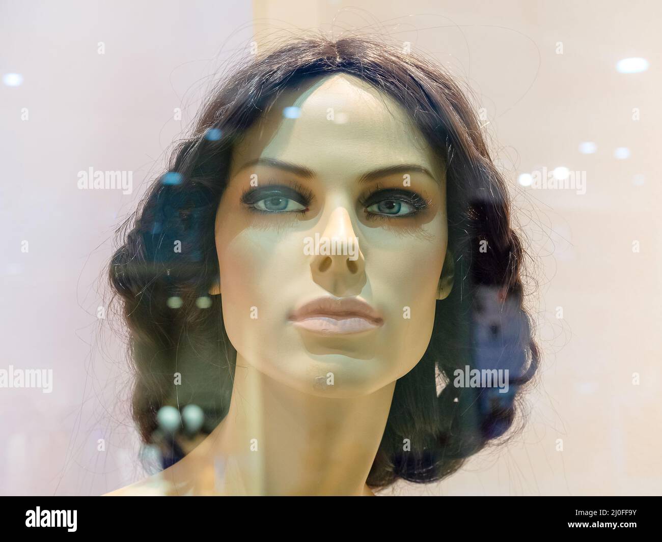 Capo di manichino femminile realistico dietro il vetro della vetrina Foto Stock