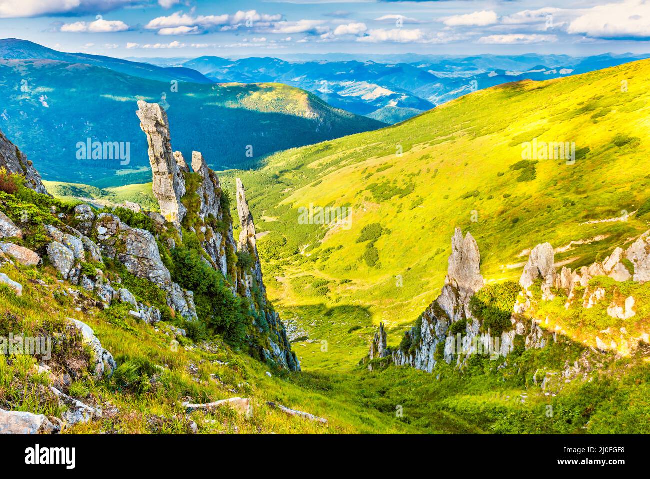 Montagne verdi e grandi rocce Foto Stock