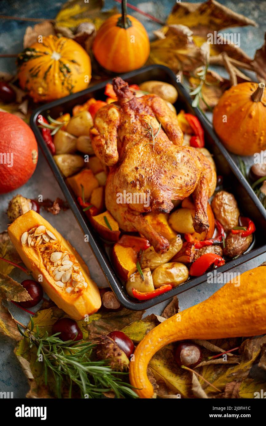 Pollo intero o tacchino arrosto con zucche, pepe e patate. Con mini zucche colorate Foto Stock