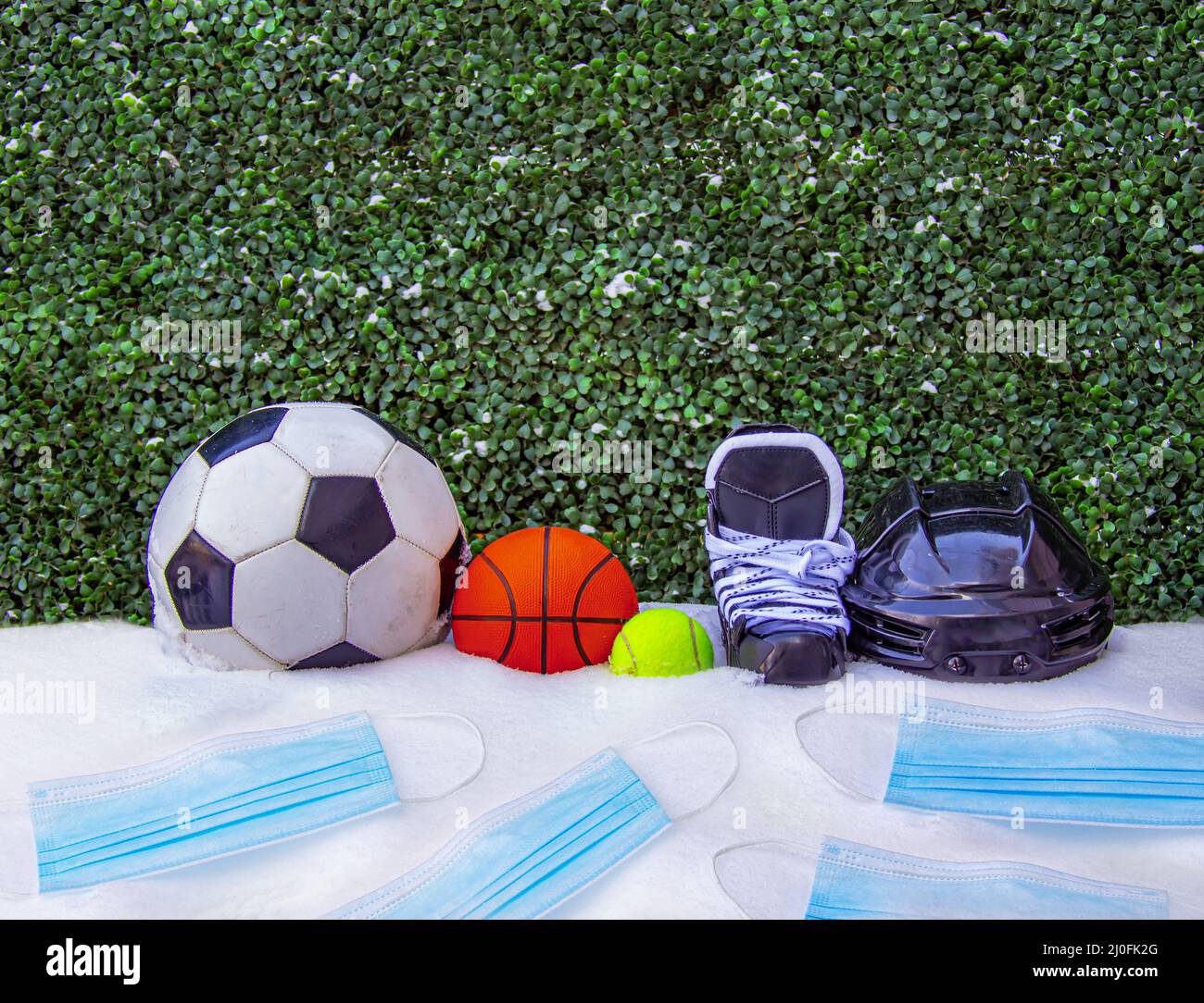 Una palla da calcio o calcio, basket ball, tennis ball, pattini con un casco sulla neve con maschere per il viso. Concetto: Sport durante l'inverno Foto Stock