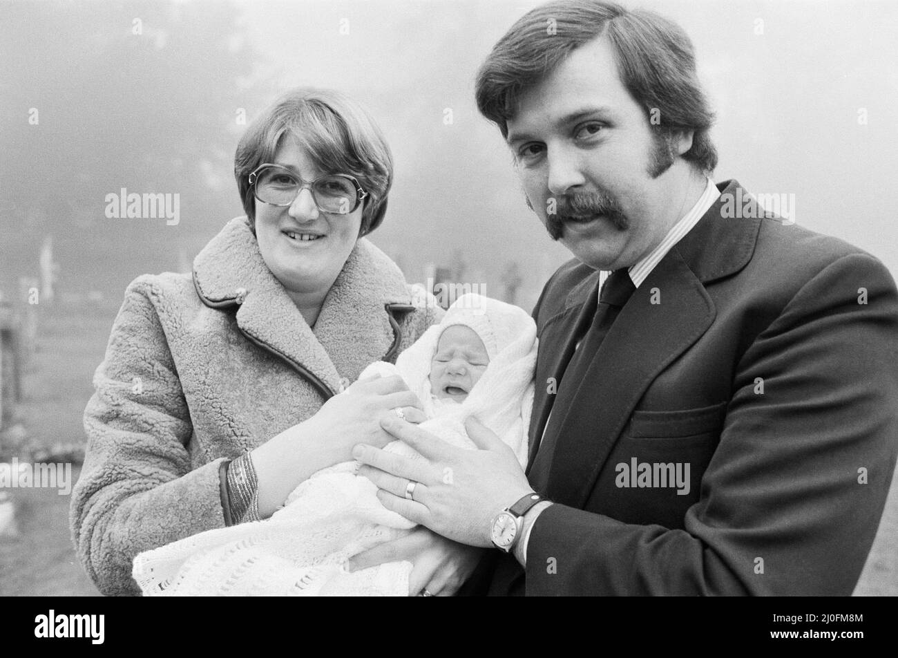 PC Graham Browne e sua moglie Yvonne posano con il loro figlio di otto settimane Clive Brown dopo la sua cerimonia di Natale alla chiesa di Sandringham, Norfolk. Alla cerimonia hanno partecipato anche i membri della Famiglia reale, tra cui la Regina, che soggiornano a Sandringham durante il periodo di Natale e Capodanno. Per coincidenza, il battesimo si è svolto negli stessi giorni del servizio familiare, portando undici membri della Famiglia reale a partecipare al battesimo. 8th gennaio 1978. Foto Stock