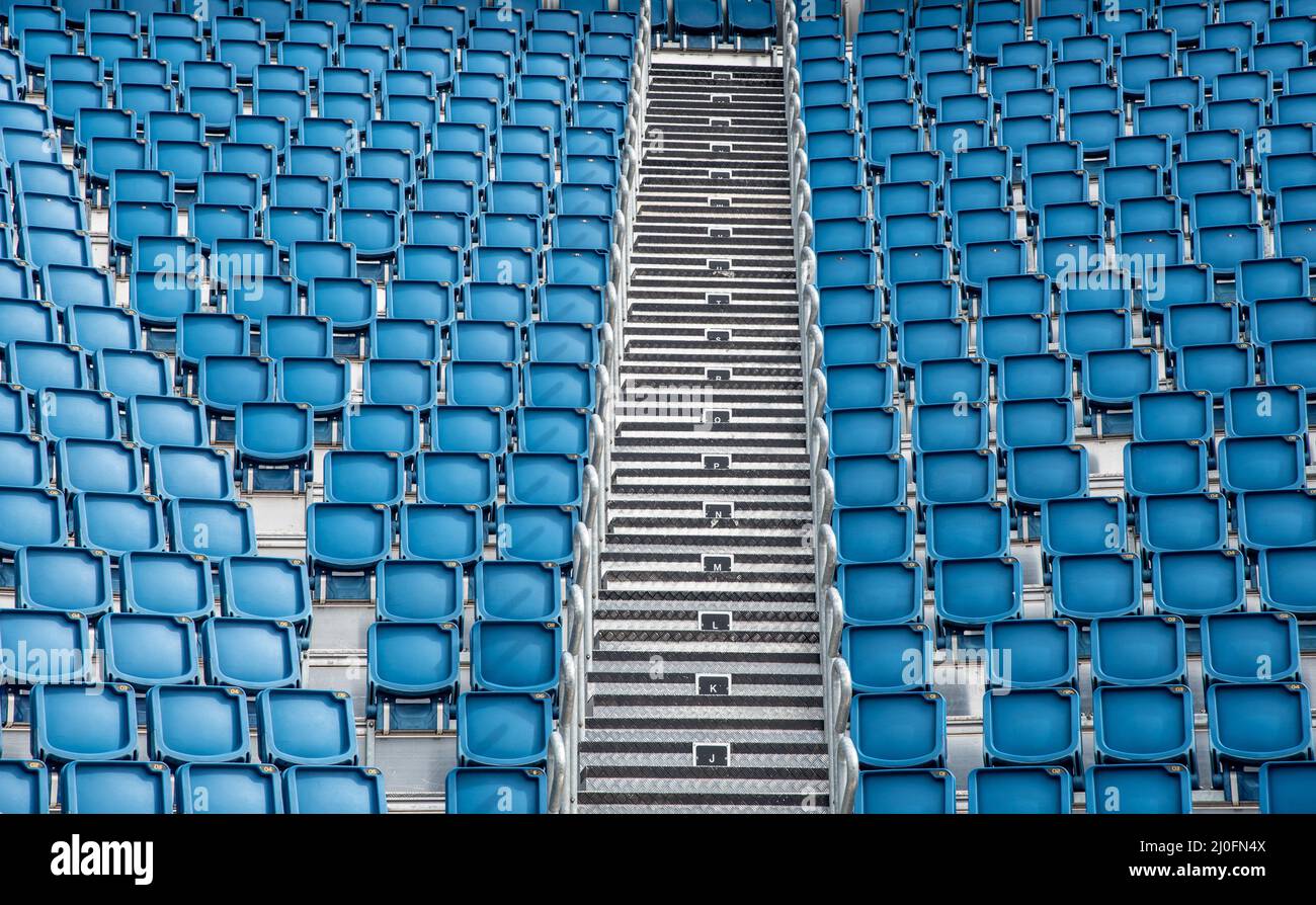 Sedie da stadio vuote in plastica blu di fila Foto Stock