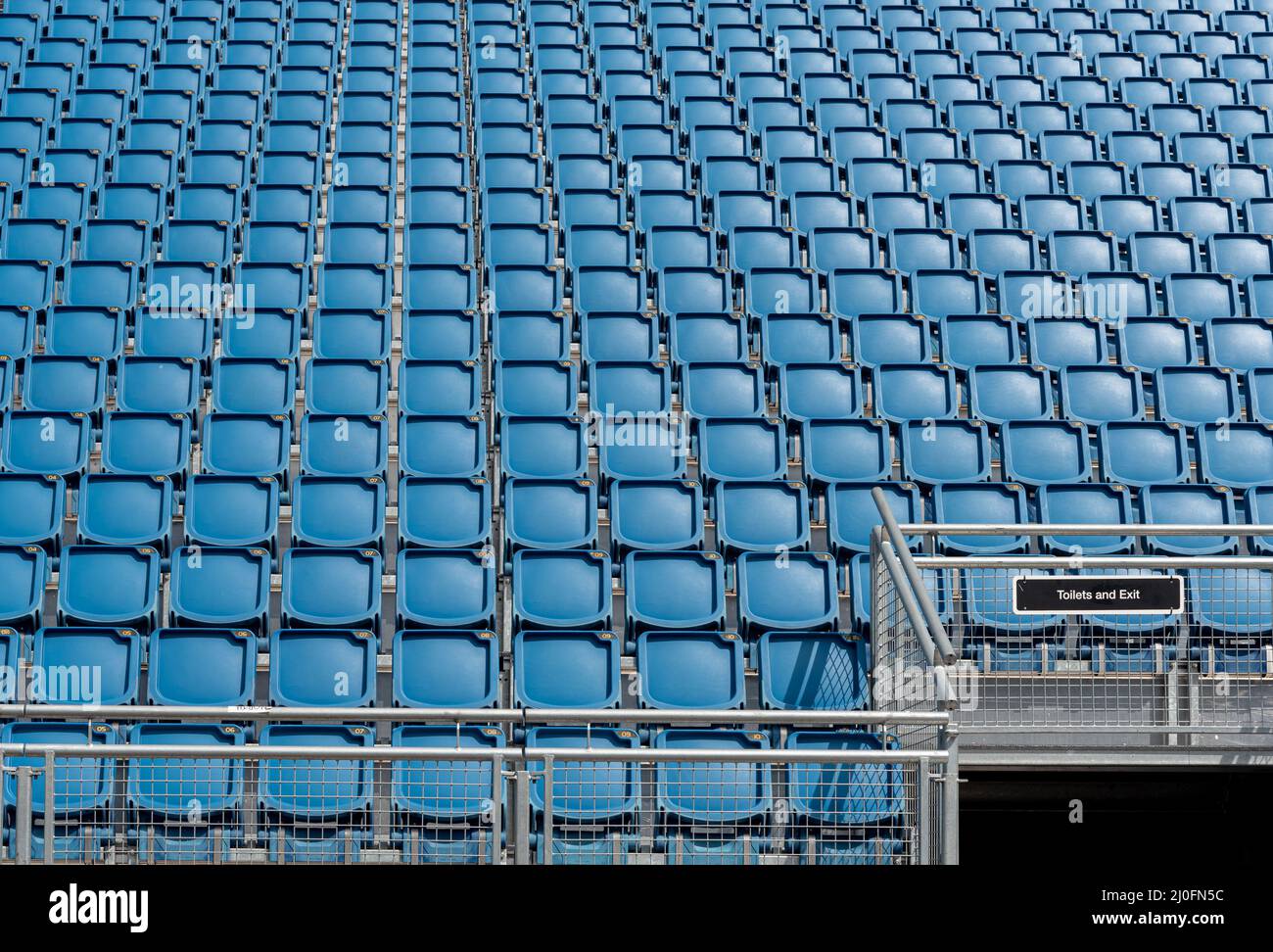 Sedie da stadio vuote in plastica blu di fila Foto Stock