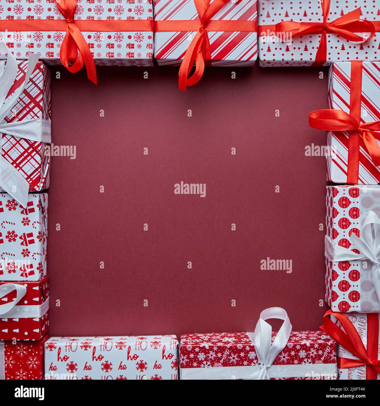 Scatole di regali arrangiate avvolte in carta festiva colorata con sopra background di burgund Foto Stock