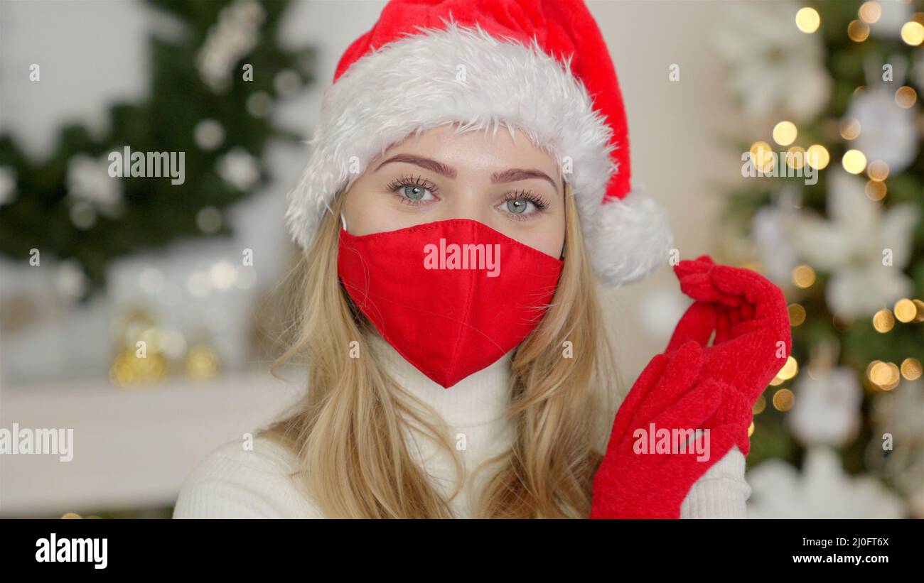 Ritratto di una bella donna nel cappello di natale. La donna indossa la maschera protettiva dal virus Foto Stock