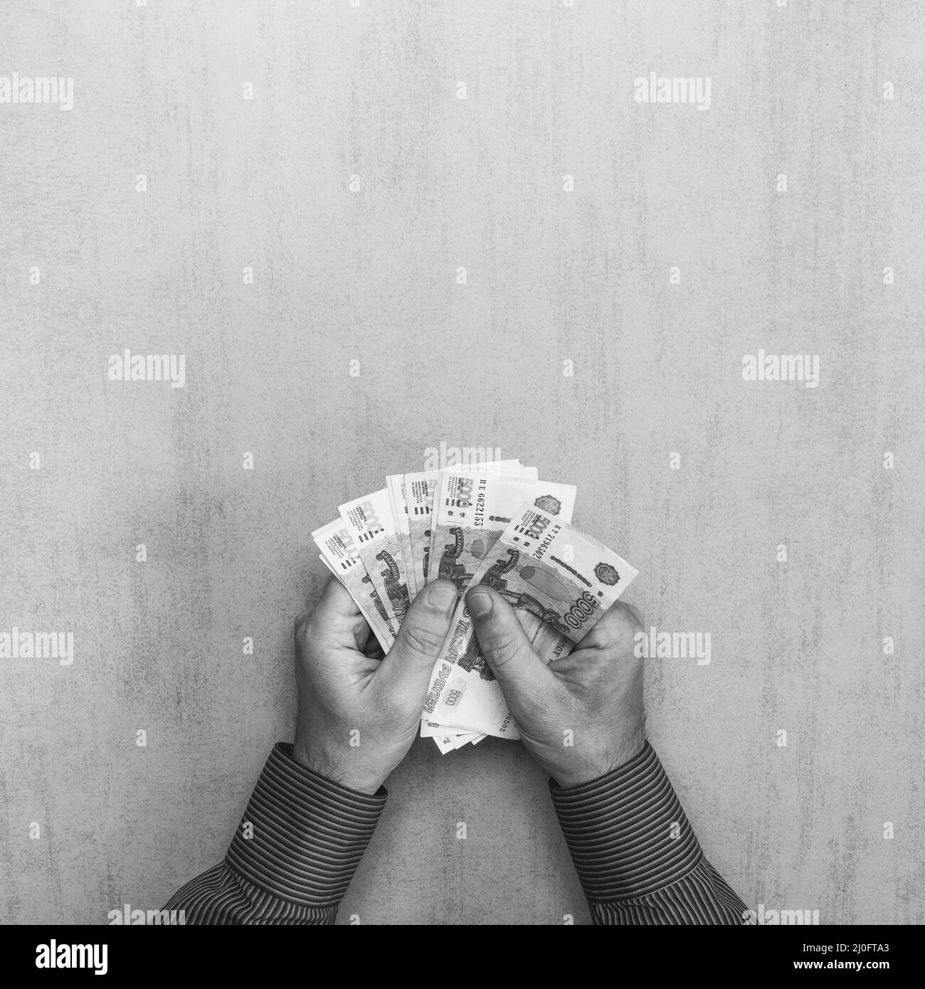 Carta cinque migliaia di banconote rubli russe nelle mani dell'uomo su sfondo grigio con spazio f Foto Stock