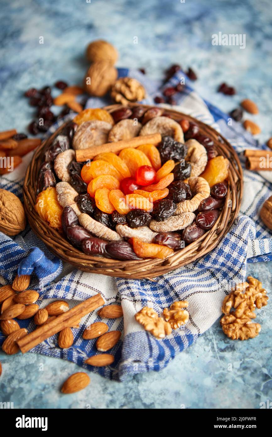 Composizione di frutta secca e noci in piccolo vaso in vimini collocato sul tavolo di pietra Foto Stock