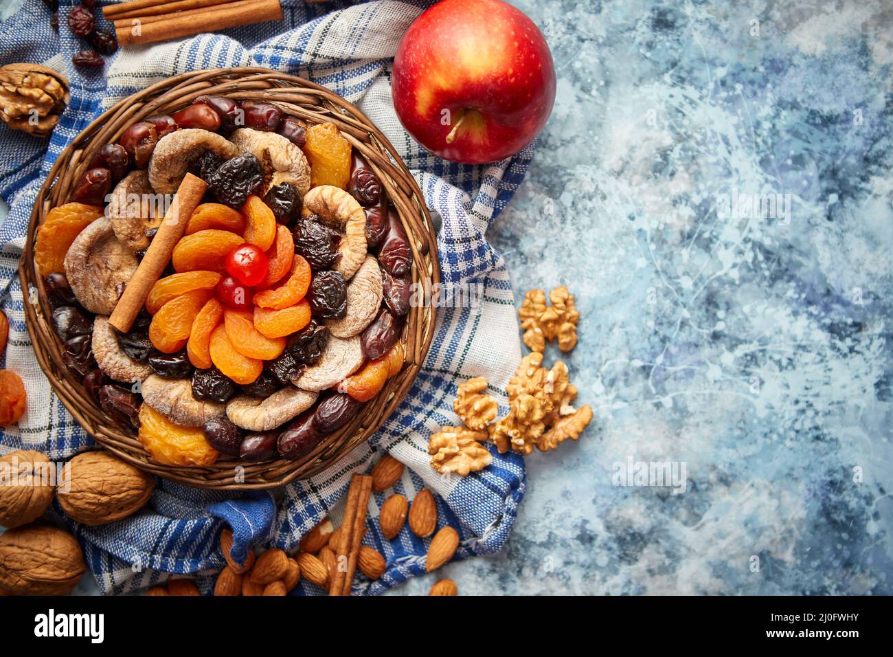 Composizione di frutta secca e noci in piccolo vaso in vimini collocato sul tavolo di pietra Foto Stock