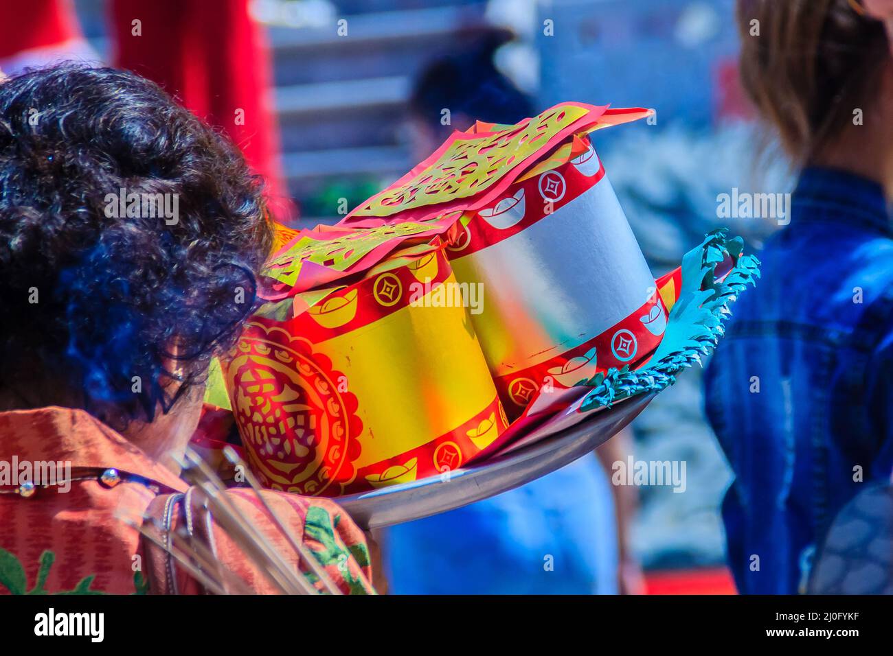 La gente con i soldi della carta, l'oro della carta ed il bastone di burla al santuario cinese per fare il merito e pagare r Foto Stock