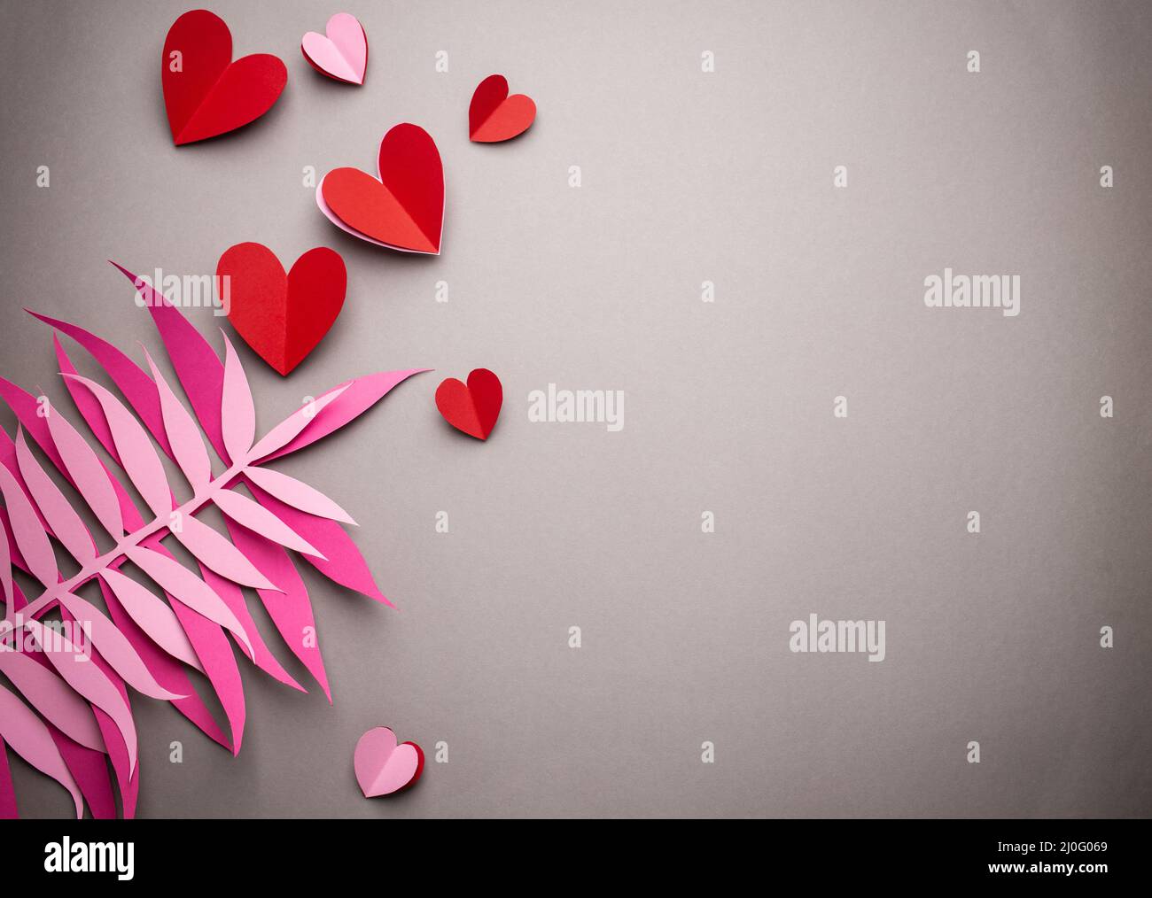 Cuori rossi tagliati da carta su sfondo rosa, carta artigianale origami stile, dall'alto. Romantico San Valentino sfondo e lov Foto Stock