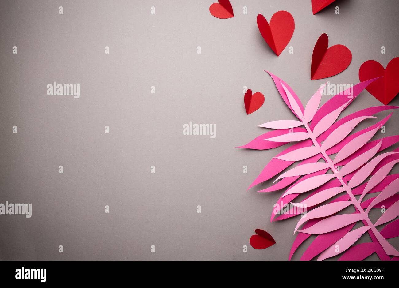 Cuori rossi tagliati da carta su sfondo rosa, carta artigianale origami stile, dall'alto. Romantico San Valentino sfondo e lov Foto Stock