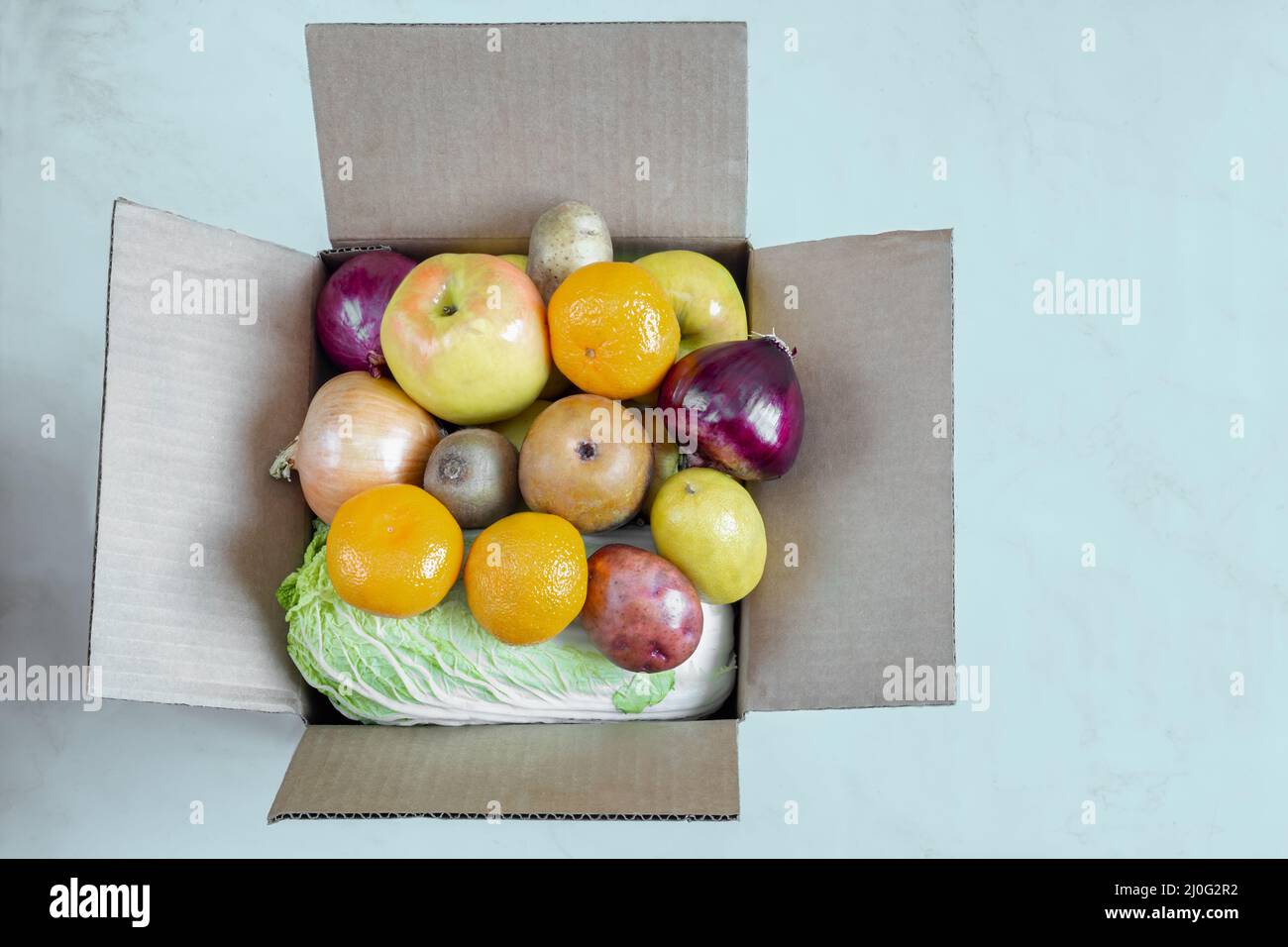 Scatola di cartone con una varietà di verdure e frutta. Foto Stock