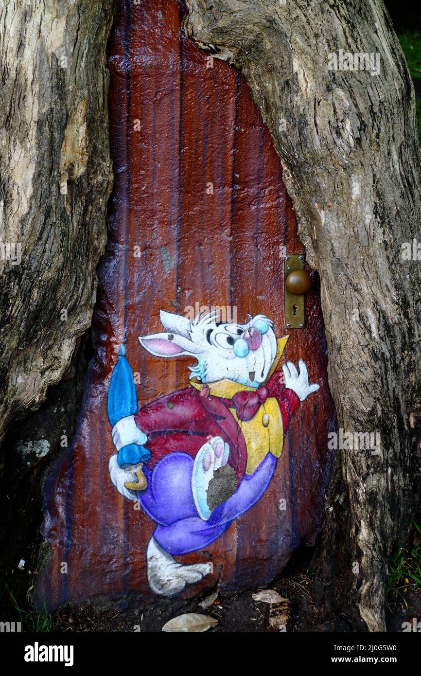 Alice in Wonderland coniglio bianco e una porta dipinta su un tronco d'albero Foto Stock