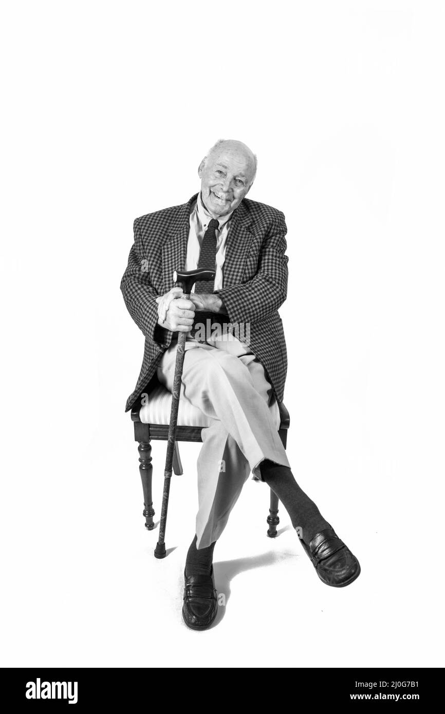 Felice anziano uomo seduto davanti a uno sfondo bianco Foto Stock