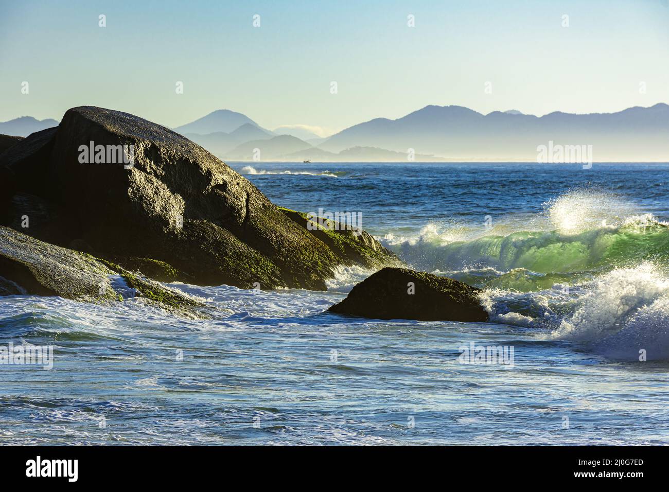 Onde che si infrangono contro le rocce all'alba d'estate sulla spiaggia del diavolo a Ipanema Foto Stock