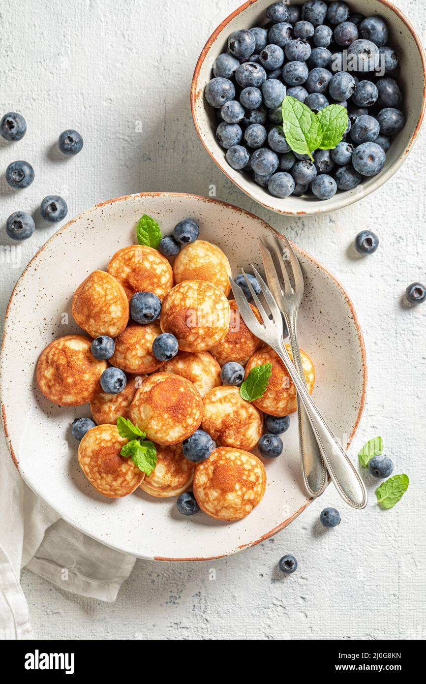 Mini pancake olandesi e dolci per colazione fresca. Colazione con mini pancake e frutti di bosco. Foto Stock