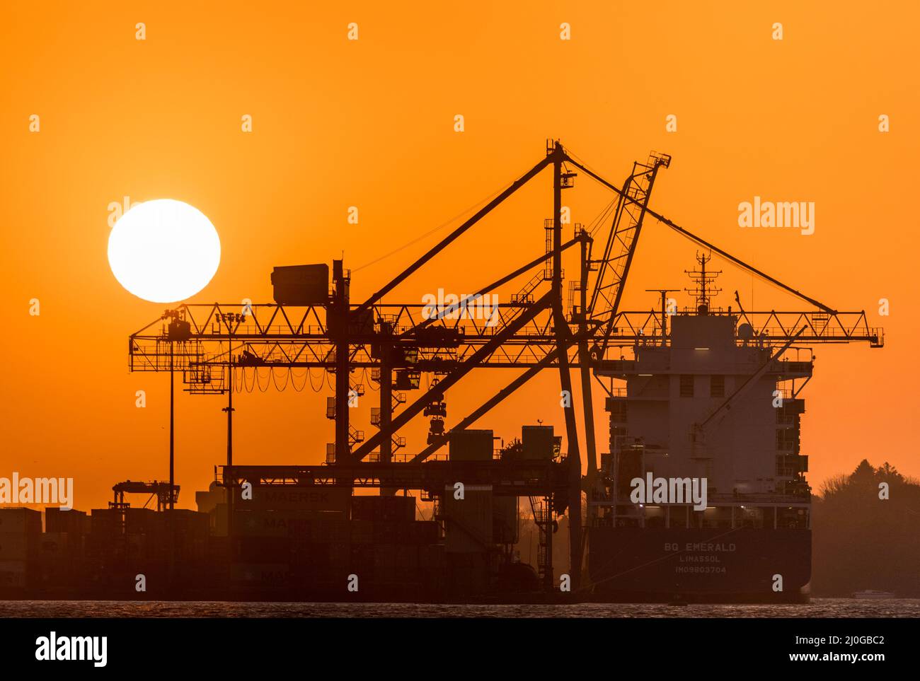 Tivoli, Cork, Irlanda. 19th Marzo, 2022.Sunrise crea una silhouette delle gru a portale e della nave container BG Emerald a Tivoli ormeggia a Cork, Irlanda. - Credit; David Creedon / Alamy Live News Foto Stock