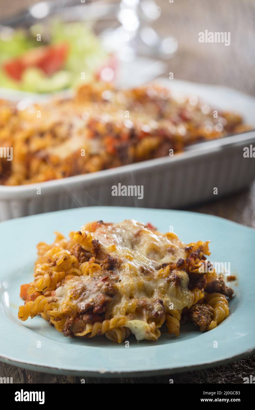 Pasta al gratin con insalata su legno Foto Stock