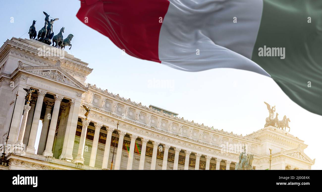 La bandiera italiana sventola nel vento con Vittoriano a Roma sullo sfondo Foto Stock