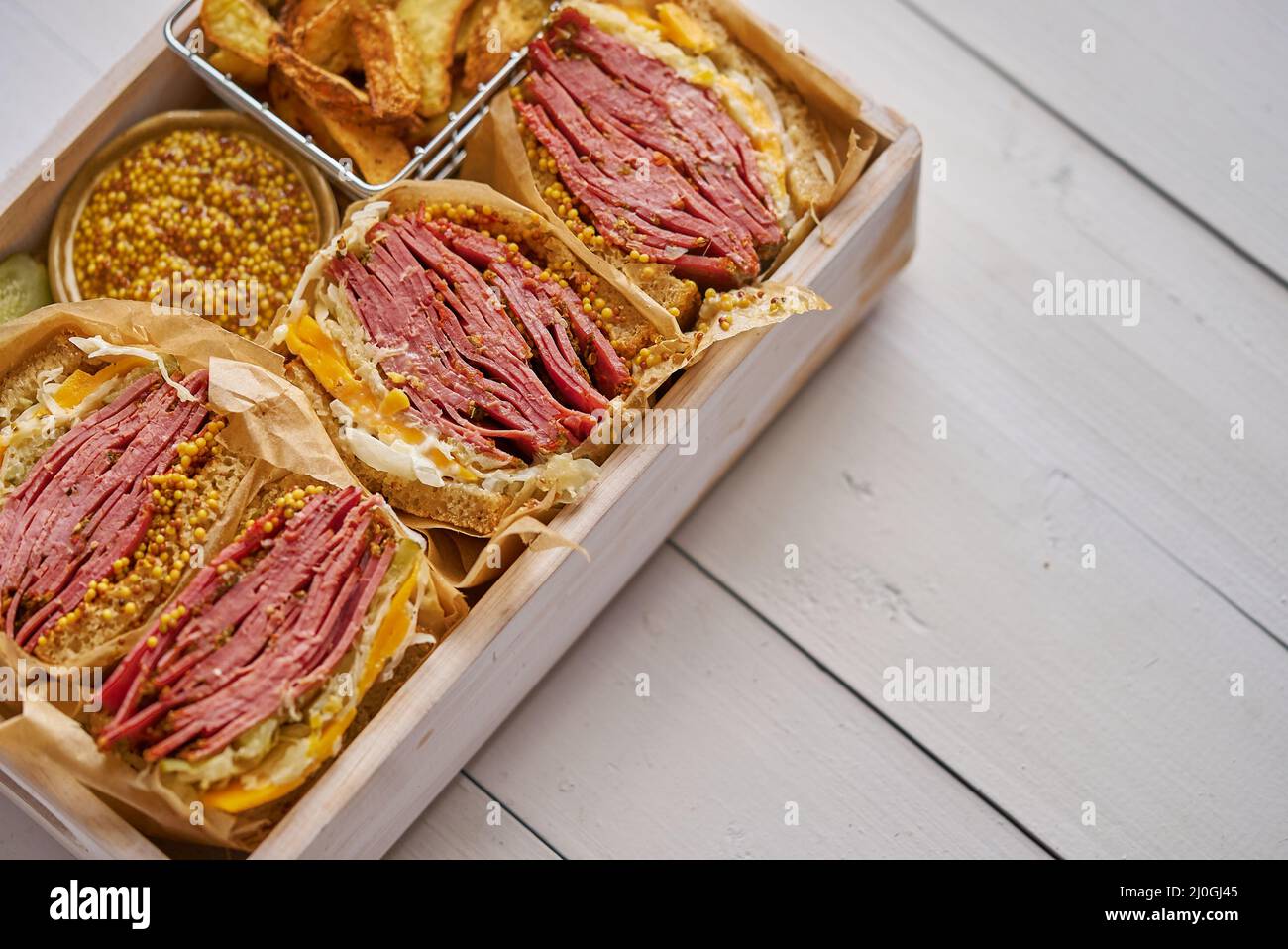 Enormi panini con pastrami di manzo in scatola di legno. Servito con patate al forno, sottaceti Foto Stock