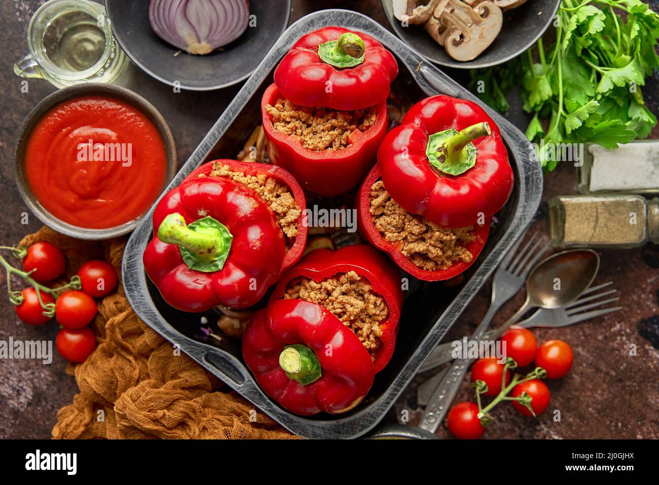 Peperoni di paprika ripieni di campana rossa in pentola da cucina con ferro da stiro vari ingredienti sul lato Foto Stock