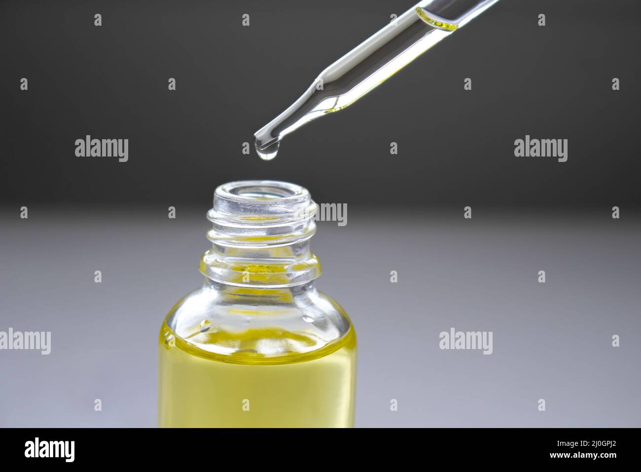 Gocciolando olio di cannabis su una bottiglia trasparente. Foto Stock