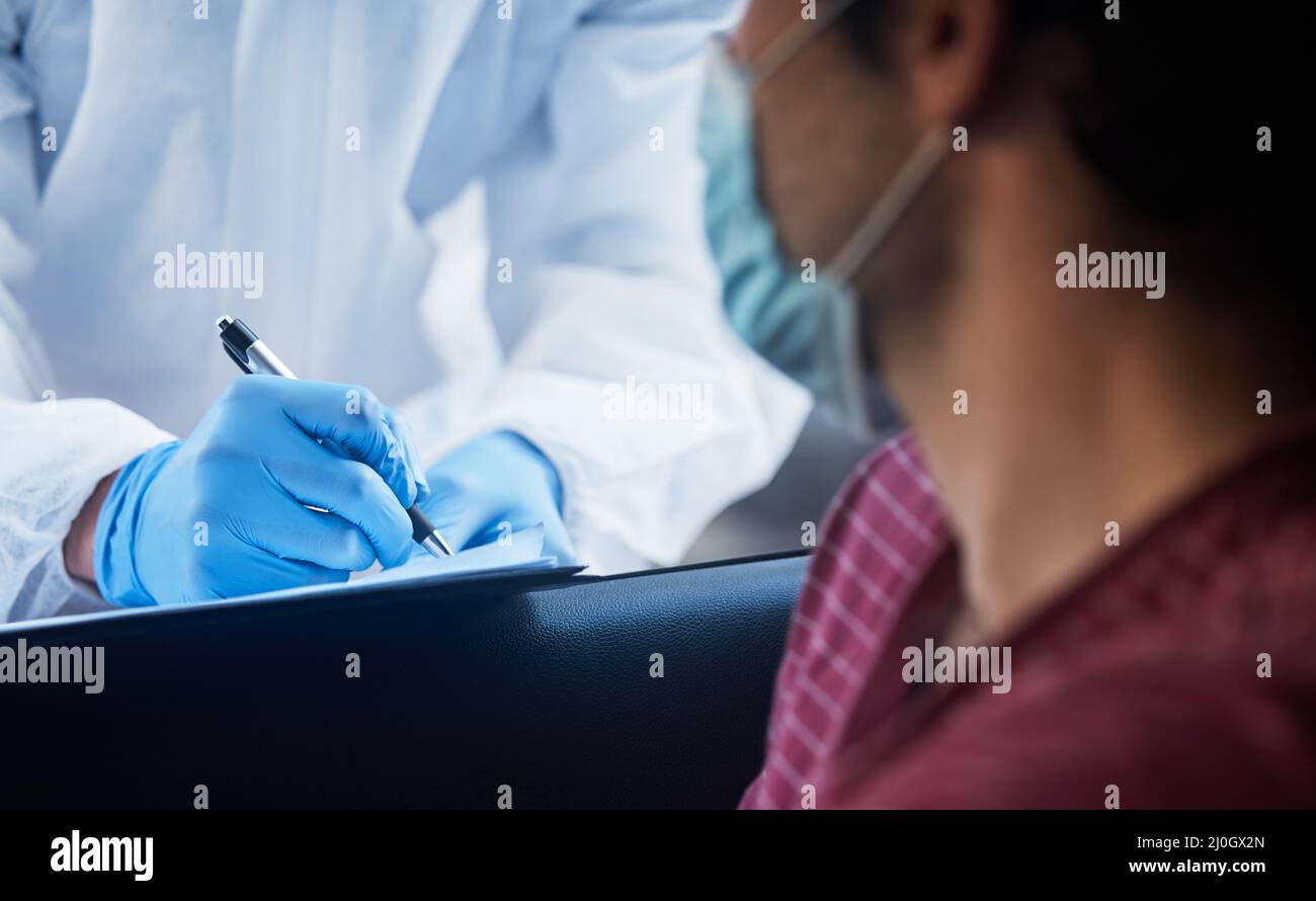 Quanto tempo da quando siete stati malati ultimi. Shot di un medico che registra le informazioni di un paziente per una vaccinazione drive-through. Foto Stock