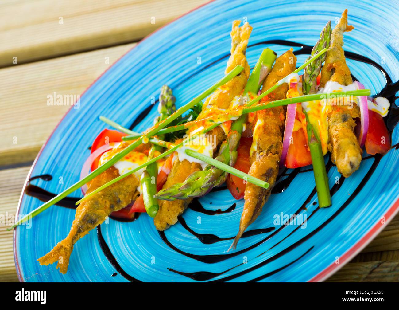 Sardine fritte in pastella con salsa di zenzero cremosa su un cuscino di pomodori dolci Foto Stock
