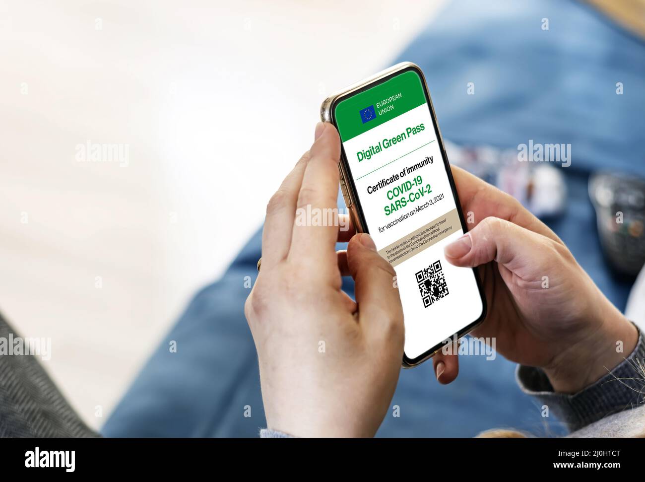 Donna che tiene uno smartphone con certificato digitale Covid-19 sullo schermo Foto Stock