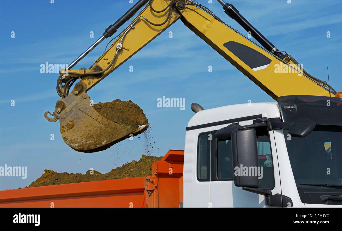 L'escavatore carica un dumper con scavo Foto Stock