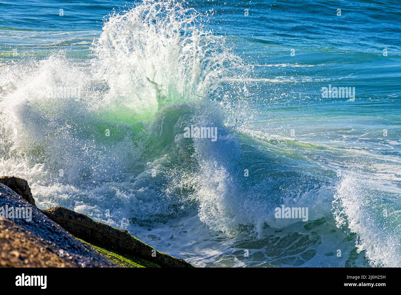 Rottura d'onda contro le rocce Foto Stock