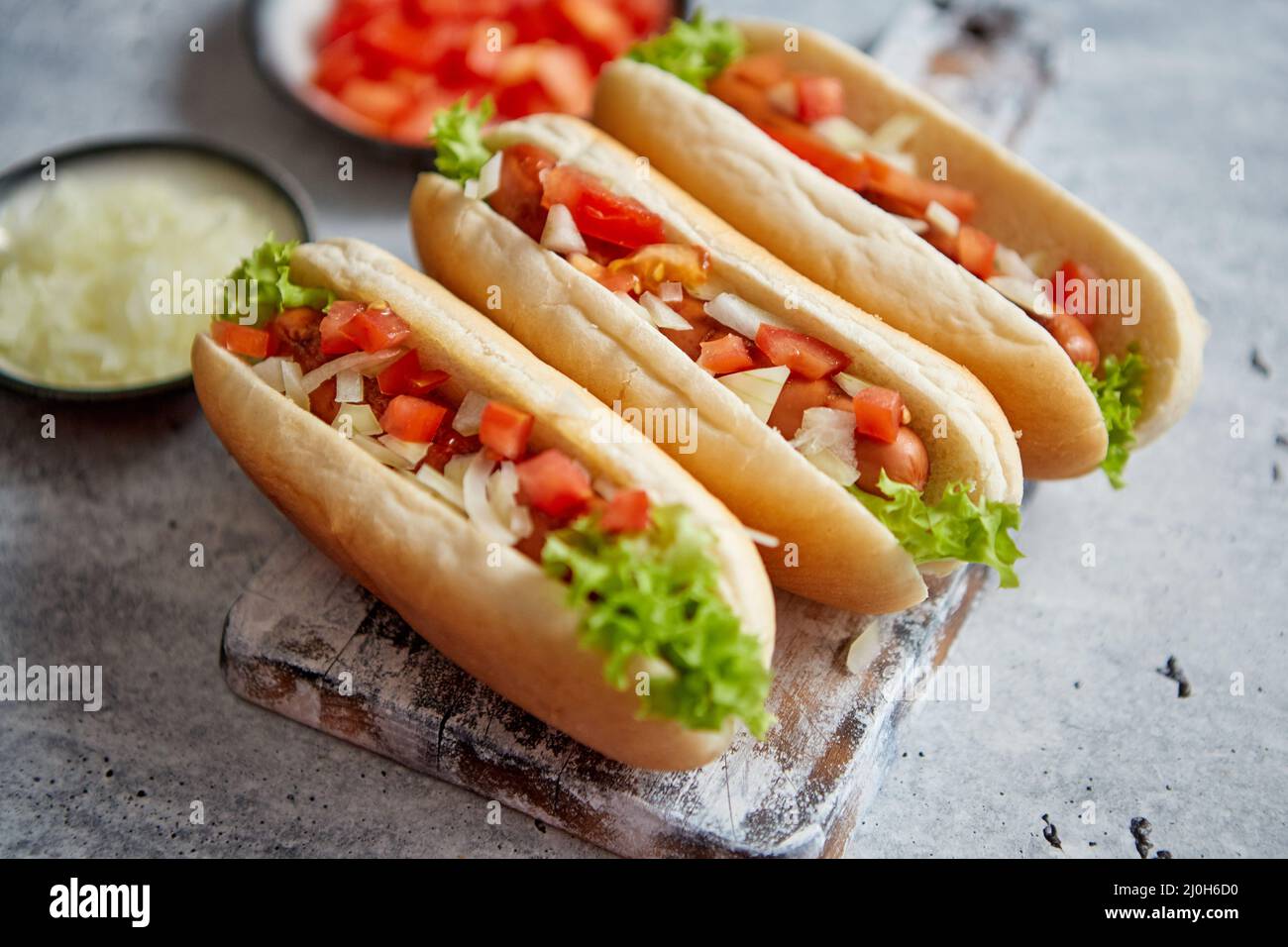 Un assortimento di tre tasety hot dogs, posto sul tagliere di legno Foto Stock