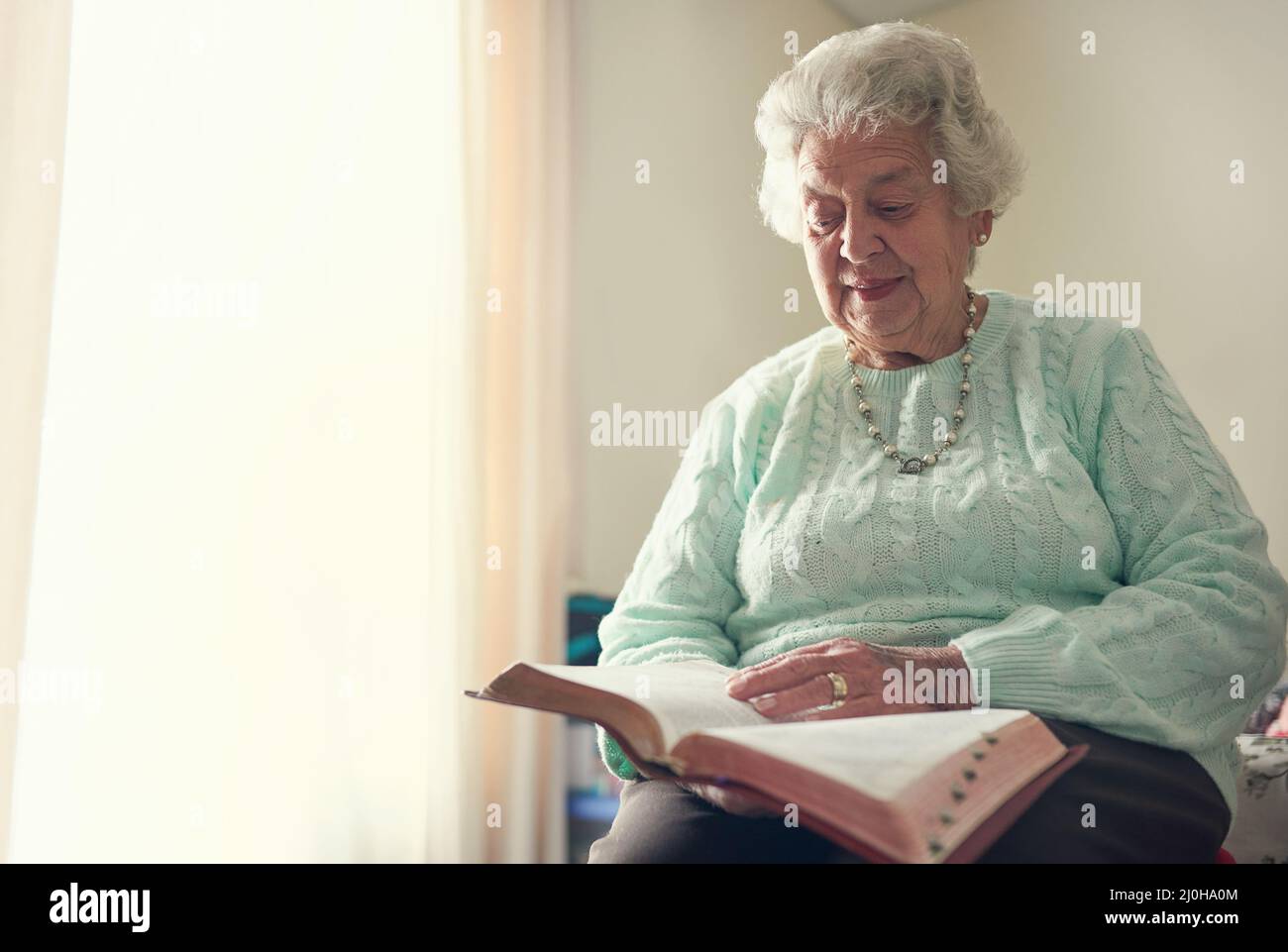 La fede è il pilastro più forte della forza. Scatto corto di una donna anziana che legge una bibbia. Foto Stock