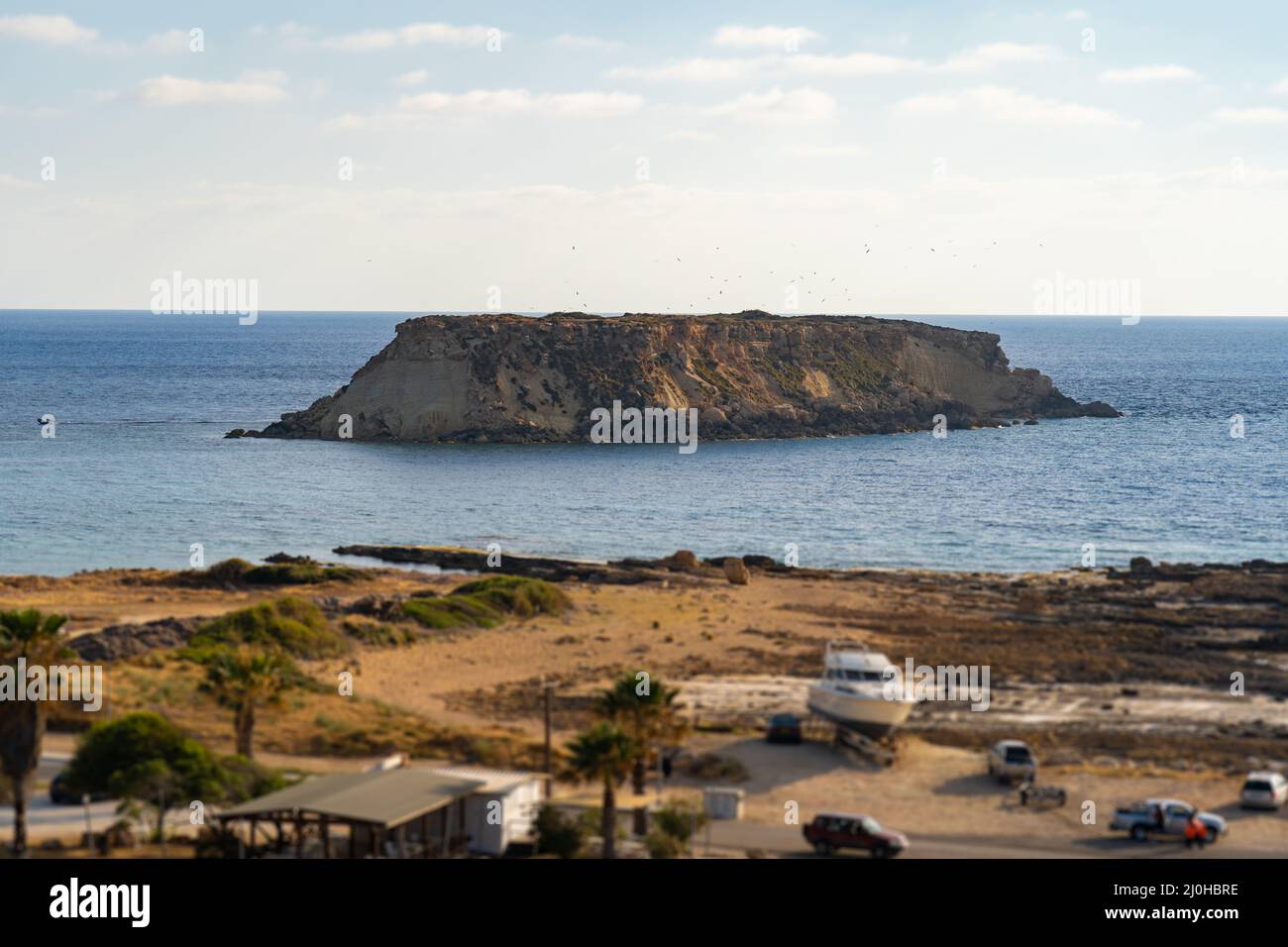 Riva rocciosa di Agios Georgios Cipro. Vista dell'isola Yeronisos. Tramonto al porto di Agios Georgios Pegeias a Paphos, Cipro. T Foto Stock